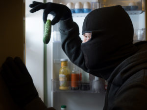 Thief. Man in black mask with a cucumber.