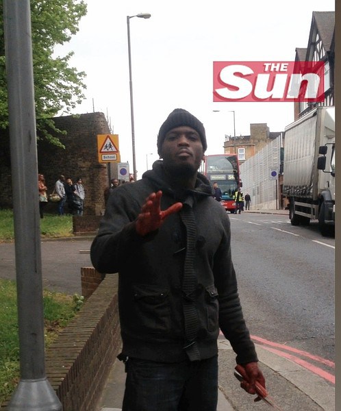 THE SUN LOGO MANDATORY: THIS IMAGE IS MADE AVAILABLE UNDER THE CONDITION THAT THE SUN LOGO REMAIN IN THE FRAME - This image taken from video made available by The Sun newspaper shows what appears to be one of the attackers speaking to the camera, holding a knife and a cleaver in his bloodied hands, after a brutal attack in broad daylight Wednesday, May 22, 2013 near a military barracks in London. The attack just a few blocks from the Royal Artillery Barracks in the Woolrich neighborhood of London left one man dead and two suspects hospitalized after a shootout with police. British Prime Minister David Cameron said the attack appeared to be terror related. There was no immediate way for The Associated Press to verify who the cameraperson was. (AP Photo/The Sun) UNITED KINGDOM OUT INTERNET OUT ONLINE OUT NO ARCHIVE NO SALES NO USE AFTER 19:30 GMT THURSDAY MAY 23