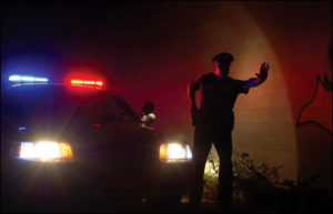 cop-in-front-of-cruiser-at-night